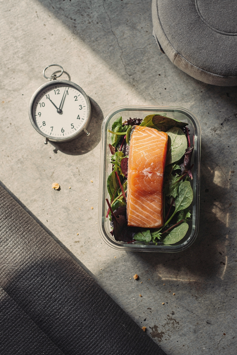 A meal prep container with salmon and greens, a yoga mat corner, a meditation cushion edge, and a Pomodoro timer