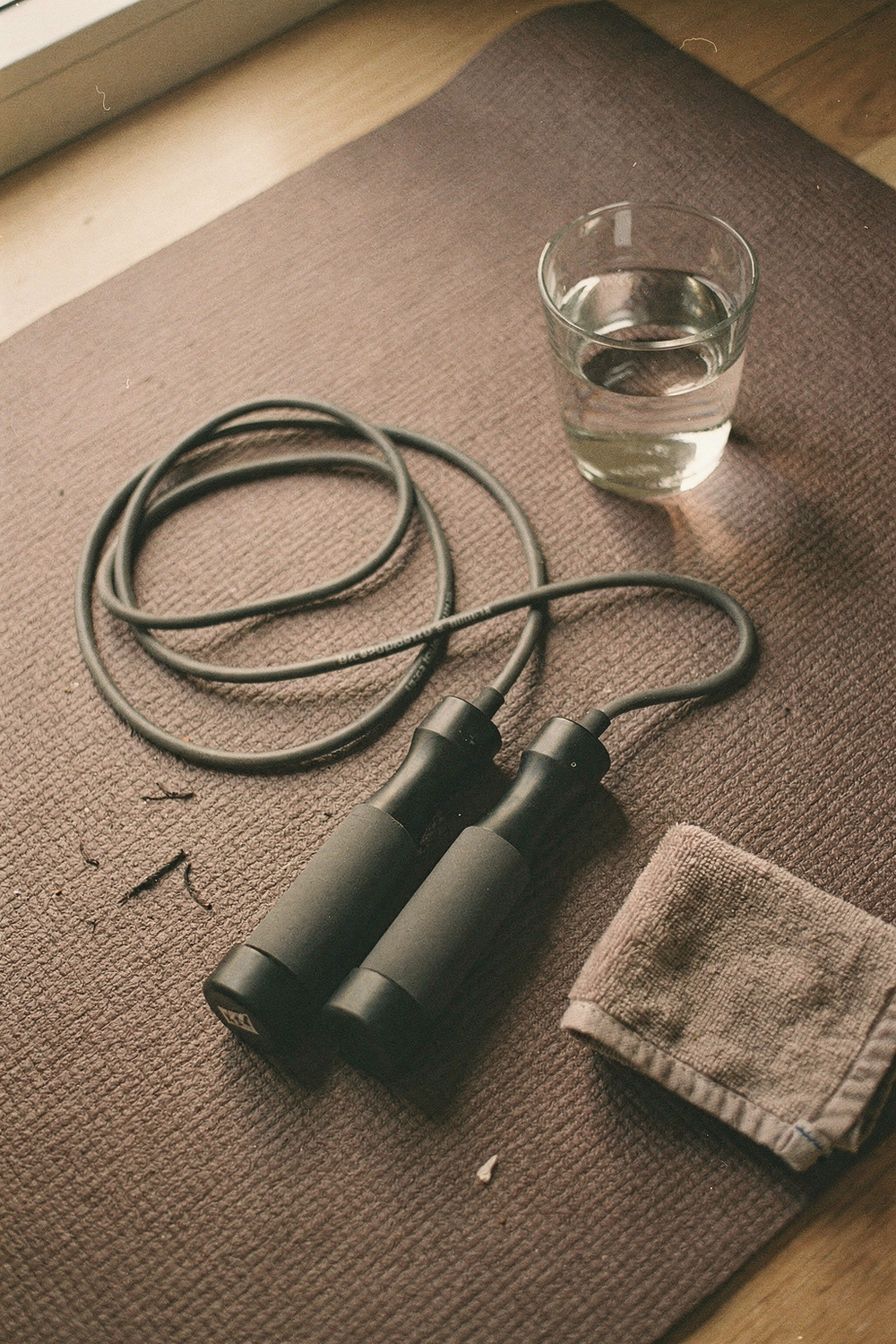 Resistance band, jump rope, water glass, and a small towel arranged casually