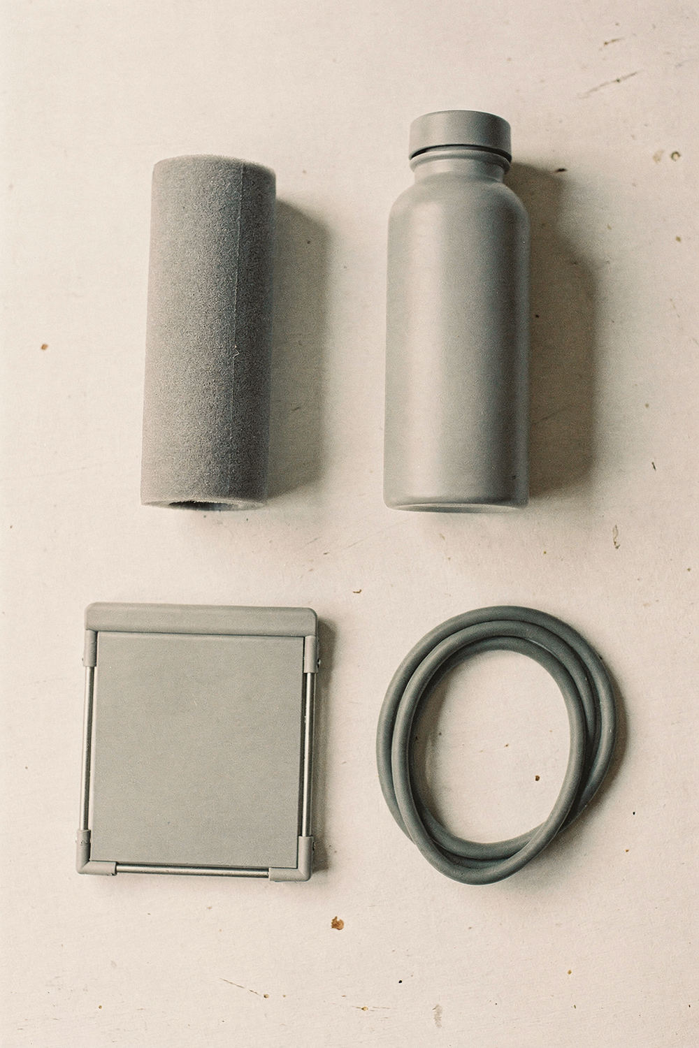 Foam roller, water bottle, standing desk riser, and resistance band arranged in a grid